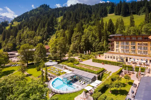 Exterior, sky view of a hotel complex with a garden in front and large hills in the background