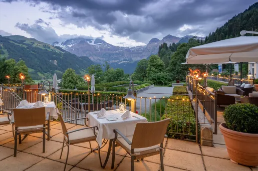 Outdoor patio with dining tables and beige chairs, with mountains in the distance