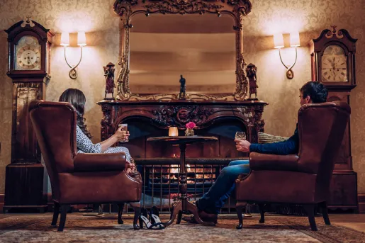 Man and women sitting on leather chairs in front of a fireplace