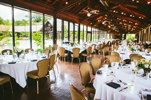 Long dining hall with circular, white dining tables and beige chairs