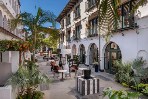 The outdoor courtyard of the Hotel Californian in Santa Barbara, featuring Spanish arched architecture and palm trees.