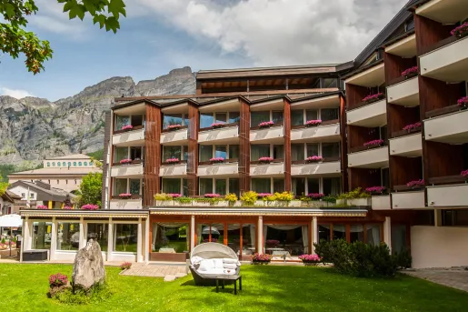Exterior view of white and brown, multi-level hotel building with a grass lawn in front
