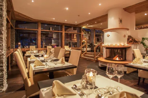 Restaurant dining area with white brown tables and beige chairs, with a fireplace in the background