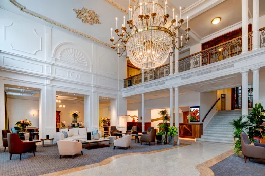 The grand, high-ceilinged interior with a multi-tiered crystal chandelier in the lobby of Grand Hotel des Bains Kempinski in St. Moritz, Switzerland.