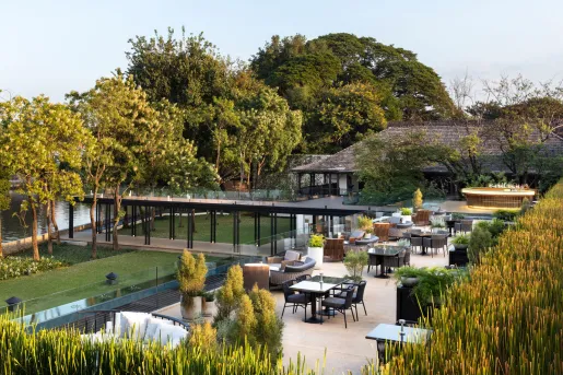 Outdoor patio and garden with chairs and tables, and large trees