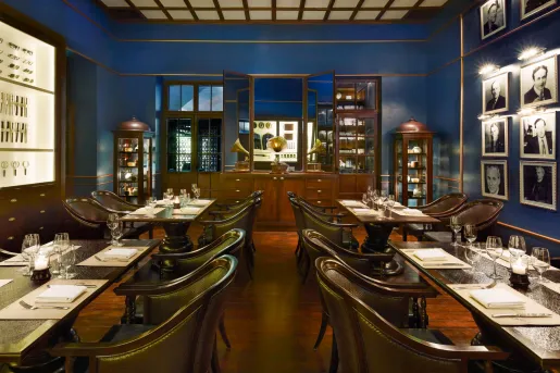 Restaurant dining area with dark, wooden chairs and rectangle tables in a blue room