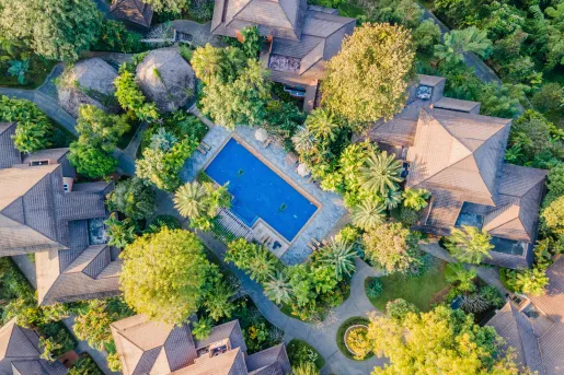 Sky view of beige buildings surrounded trees and an outdoor pool