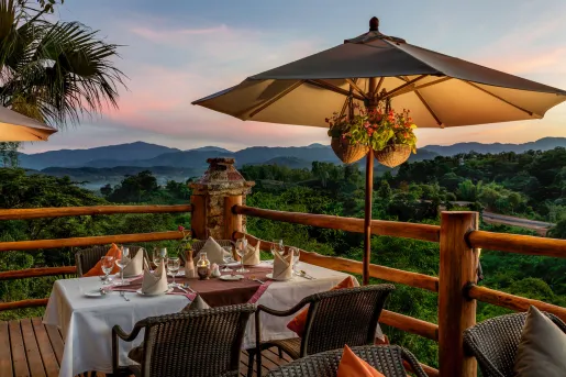 Outdoor patio and balcony, with white dining tables and a beige umbrellas