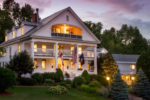 The three-story exterior with grand columns and multi-level wrap-around porches of Rabbit Hill Inn in Lower Waterford, Vermont.