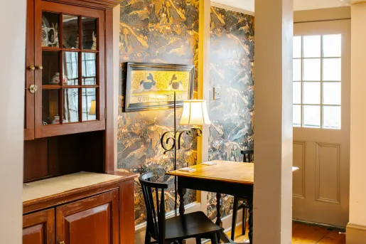 A room featuring traditional dark wood furniture and landscape-themed wallpaper at Rabbit Hill Inn in Lower Waterford, Vermont. 