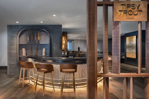 The bar at The Lodge at Spruce Peak in Stowe, Vermont, with natural wood elements and modern bar stools.