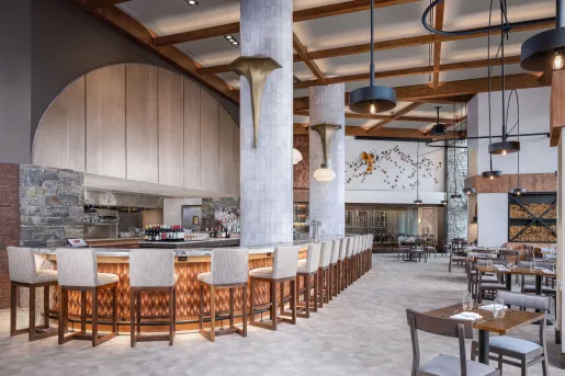 The restaurant at Spruce Peak in Stowe, Vermont, that features high ceilings with wooden beams and extensive bar seating.