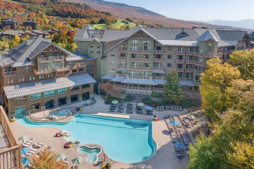 The Lodge at Spruce Peak in Stowe, Vermont, featuring its large outdoor swimming pool and mountain views.