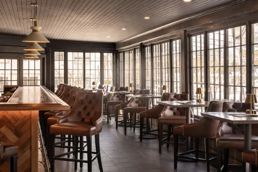 The interior of the bar at The Wentworth Inn in Jackson, New Hampshire, which features a modern-day tavern ambiance with dark wood and leather seating