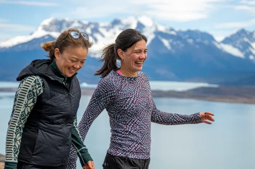 Two women smiling while walking in front of a large lake