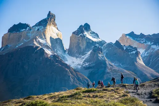 Large mountains with a group of people walking on a smaller mountain