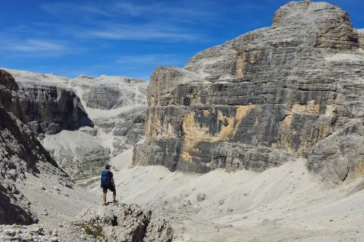 Man standing on a cliff, looking out towards large, gray and brown mountains