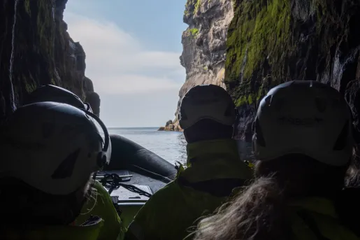 Group of people on a raft, paddling through a cave
