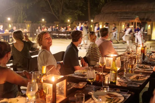 Group of men and women smiling while sitting at dining tables outdoors