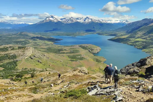 Group of people descending a gravel trail, with views of a valley and large lake