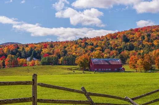 A vibrant red barn set against fall foliage in Vermont