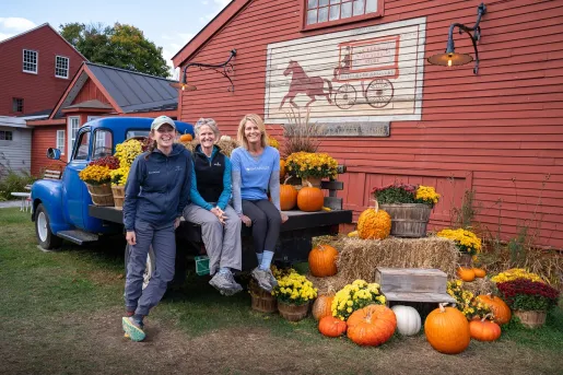 A family sits on a vintage blue truck surrounded by pumpkins and yellow flowers at the Vermont Country Store in Rockingham, Vermont.