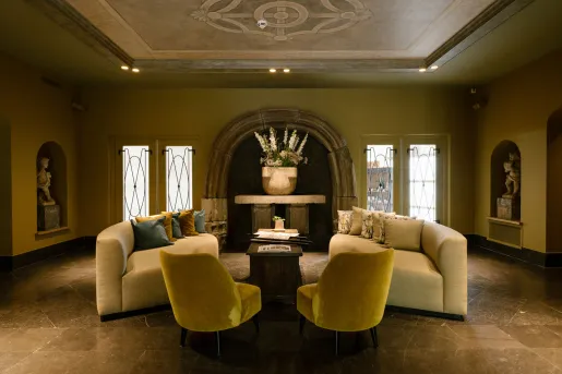 Dimly lit lounge area with beige, cushioned sofas and sculptures along the walls