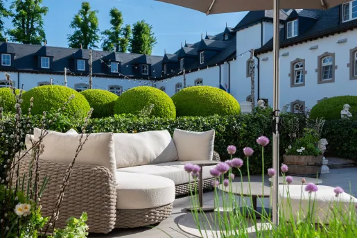 Outdoor patio with cushioned sofas and a large building in the background