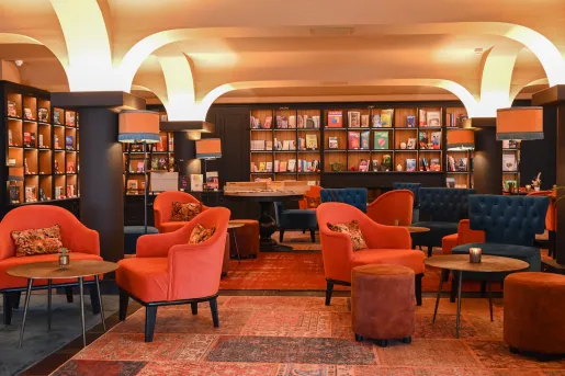 Indoor lounge area with orange, cushioned chairs and circular tables
