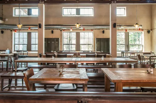 Rustic wood tables and chairs along with high ceilings and metal beams inside the restaurant at Boutique Hotel Latrán in Český Krumlov, Czech Republic.