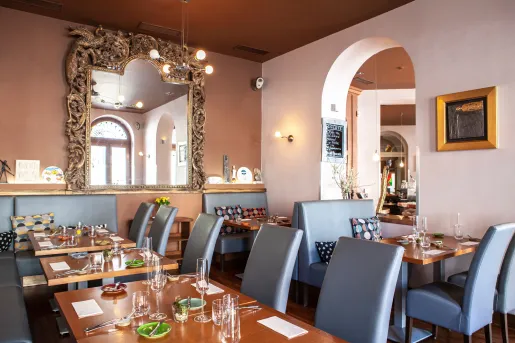 Restaurant dining area with long, wooden tables with gray chairs