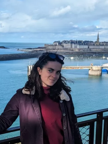 Woman standing on a bridge overlooking the ocean