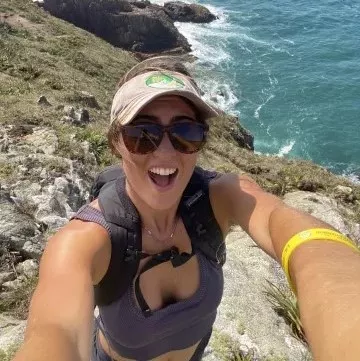 Woman smiling with a cliff and ocean in the background