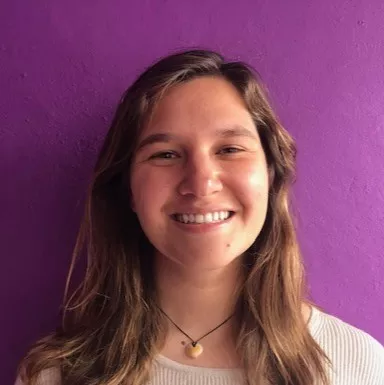 Woman smiling in front of a purple wall