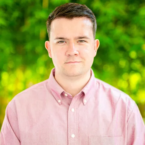 Headshot of man wearing a pink button up shirt