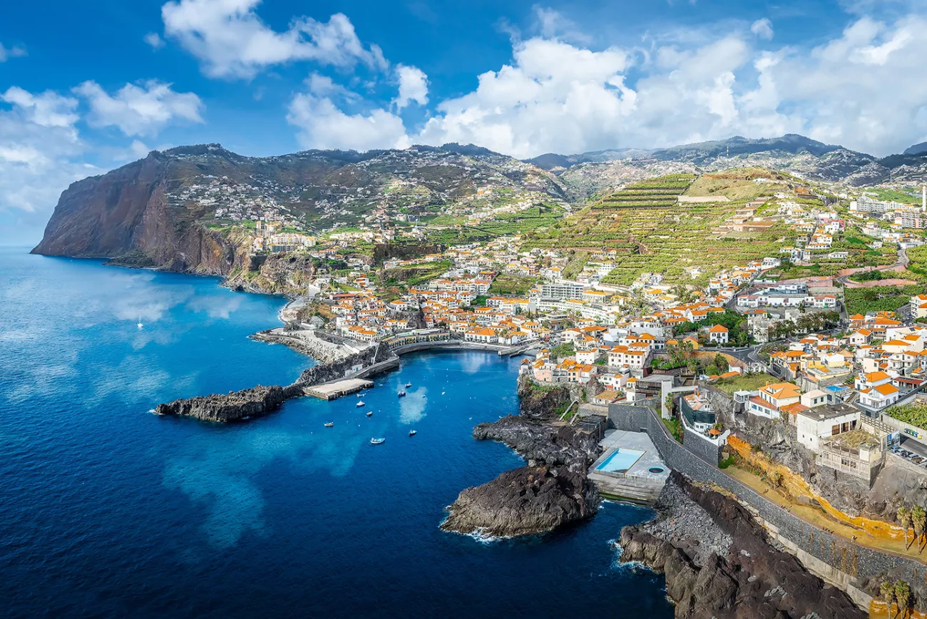Sky view of a oceanside town with large mountains in the background