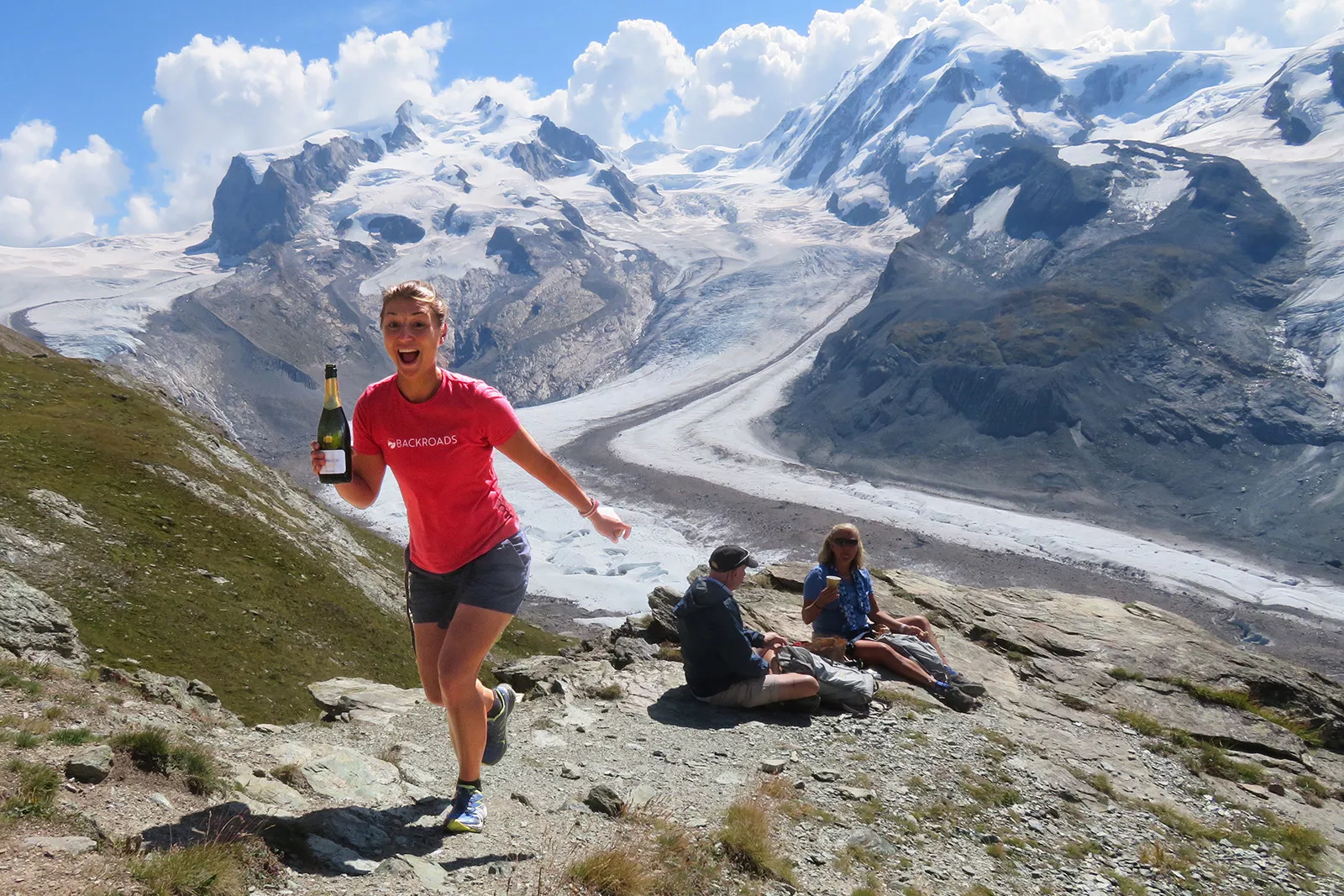 Woman holding a bottle of wine ascending a mountain