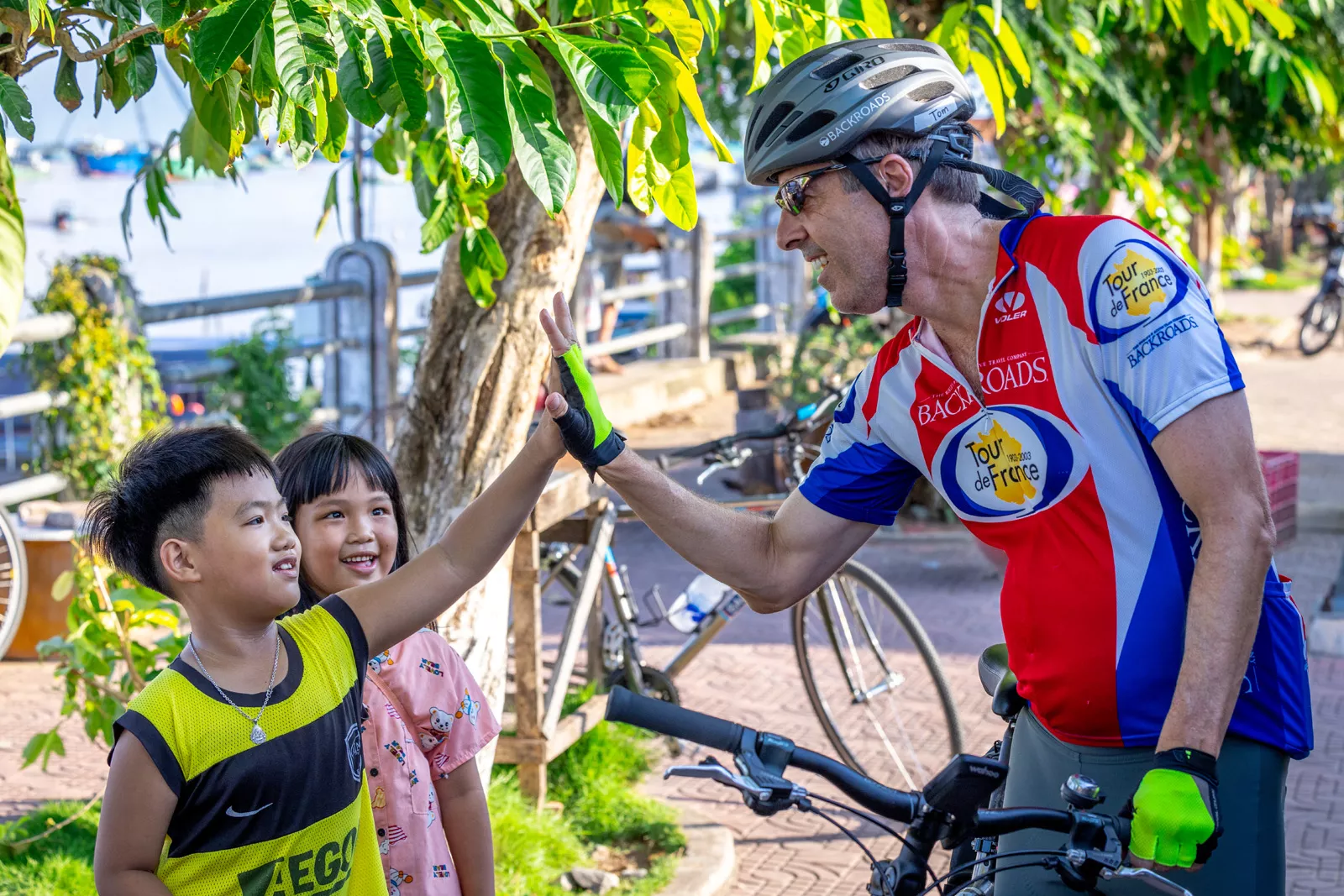 Man riding a bike while giving high fives to little kids
