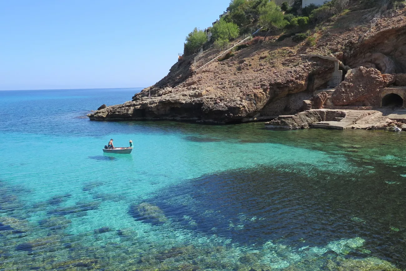 Two people on a small boat on the coast of the ocean