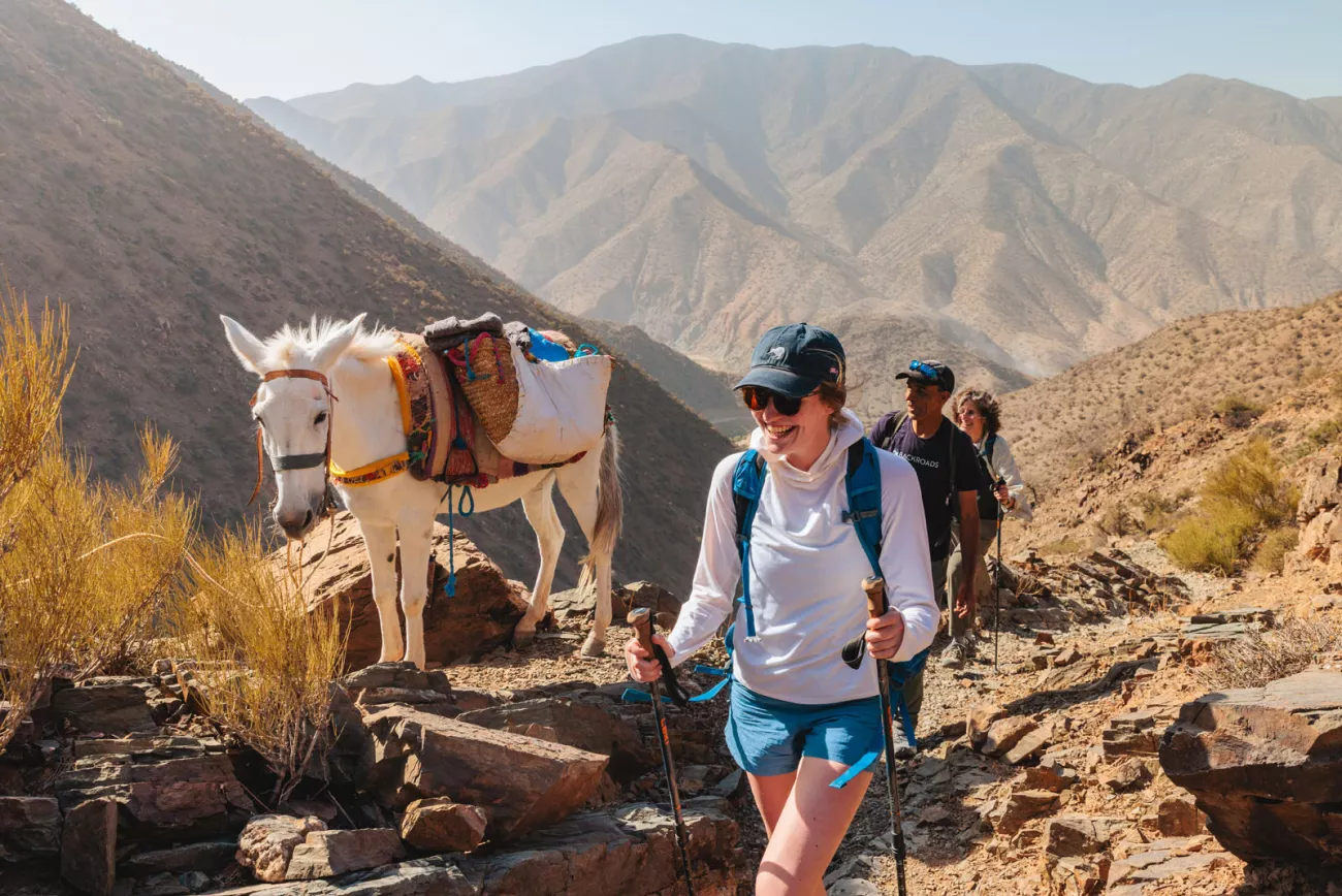 Group of people smiling while hiking next to a white horse