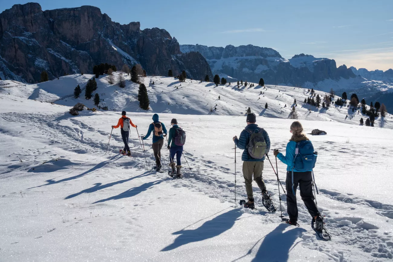 Group of hikers walking through a snowy valley with tall mountains in the distance