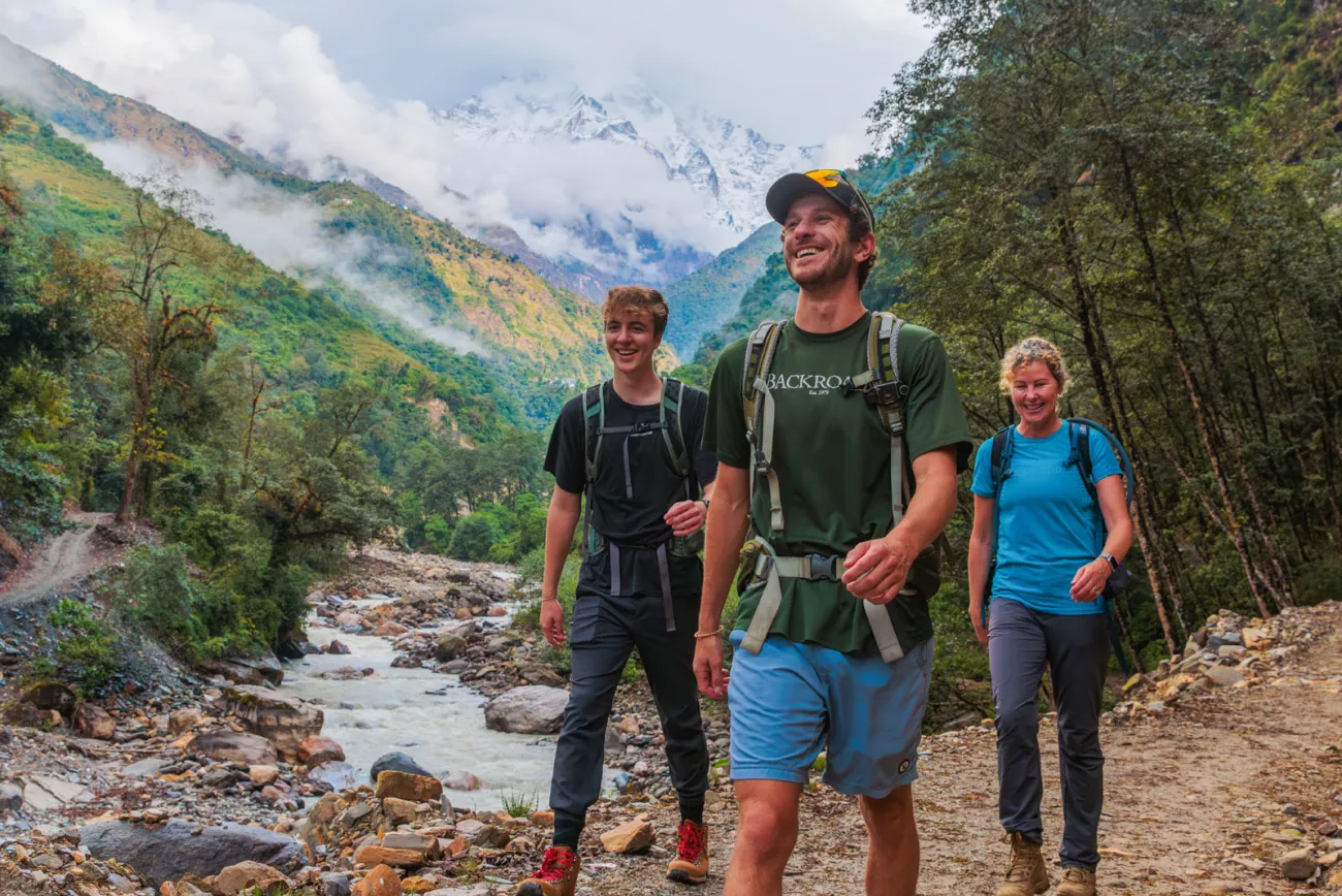 Two men and one woman walking along a frozen river with a forest in the background