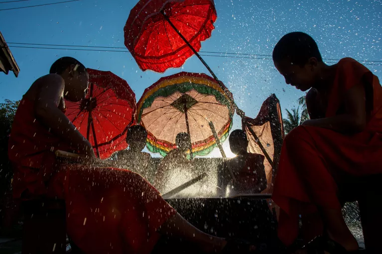 novice monks beating a new dry with palm reeds and splashing water