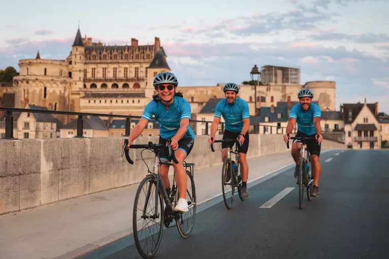 Three guests cycling in French town, Château Royal d'Amboise in background.