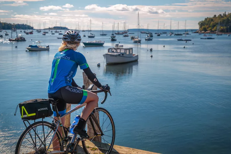 Guest with bike on pier, overlooking bay full of sailboats.