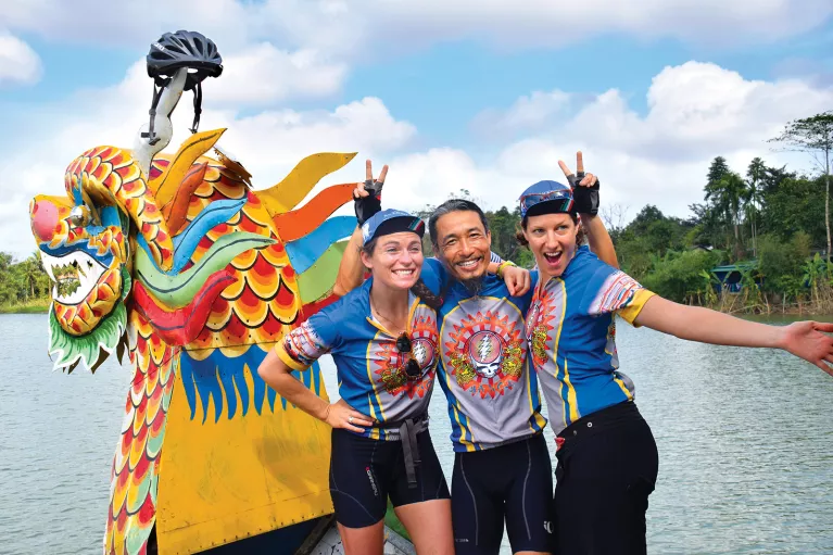 Three Backroads leaders laughing and posing in front of a dragon boat