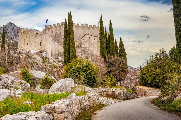 Shot of road leading to white brick castle structure. 