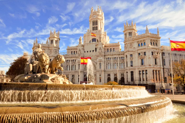 Shot of the Plaza de Cibeles, Spanish flags flying around it.