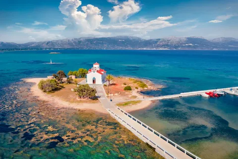 Shot of small island with church, two roads leading onto it, amidst ocean vista.