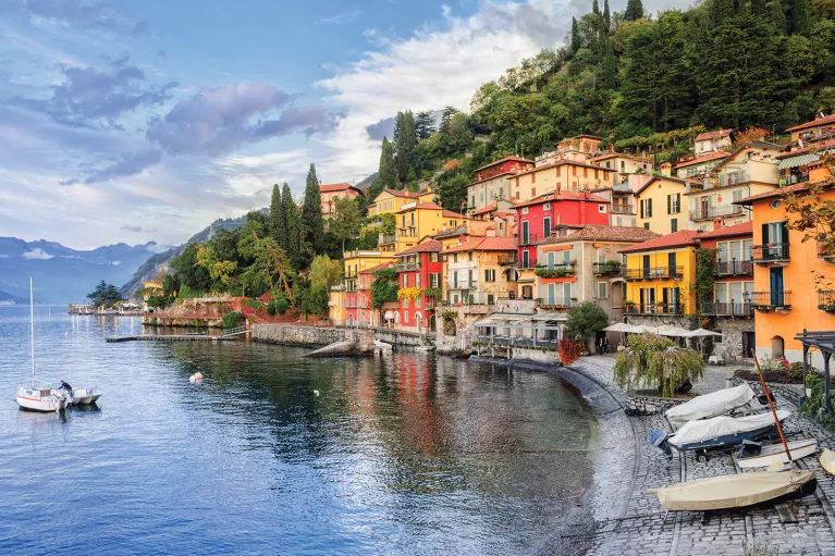 Wide shot of Lake Como coastline, colorful houses.